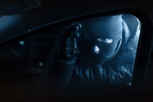 Car robber at night looking inside a car